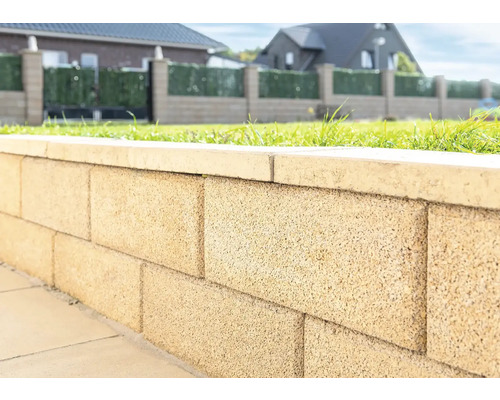 Nahaufnahme einer Gartenmauer aus Betonsteinen mit Abdeckung.