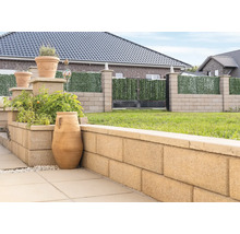 Gartenansicht mit Pflanzkübeln, Mauer aus Betonsteinen und Zaun mit Sichtschutz