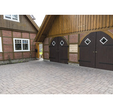 Einfahrt mit Pflastersteinen vor einem Haus mit Holztor und Holzelementen