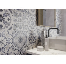 Badezimmer mit Wandfliesen im Patchwork-Design, Waschbecken, Armatur und Spiegel