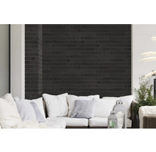 Wohnbereich mit Wandverkleidung aus schwarzen Ziegelsteinen und weißem Sofa mit Kissen