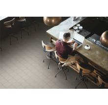 Heller, gefliester Boden in einem Café mit einem Mann, der an einem Tresen mit Laptop sitzt.