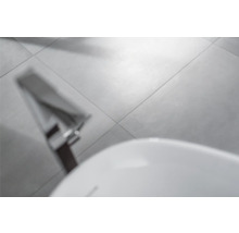 Graue Bodenfliesen im Badezimmer mit Badewanne und Armatur