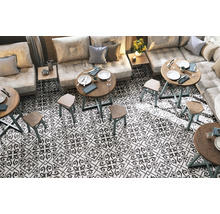 Innenraum mit Bodenfliesen im Retro-Stil, Tischen und Sitzgelegenheiten.