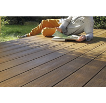 Person liegt auf einer Holzterrasse und liest ein Buch.