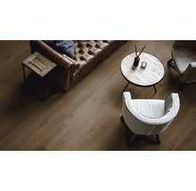 Wohnzimmer mit braunem Ledersofa, Holztischen und Holzboden.