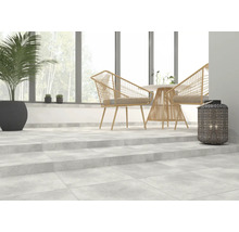 Heller Raum mit Betonfliesen, Rattansesseln, Tisch und Dekoration