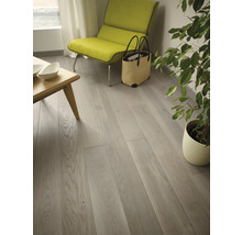 Helles Wohnzimmer mit Holzboden, Sessel und Zimmerpflanze