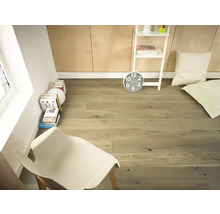 Heller Raum mit Holzboden, Leiterregal, Uhr, Kissen und Stuhl.