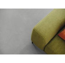 Ein grauer Boden und ein grünes Sofa sind zu sehen.