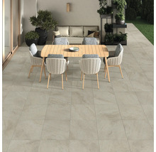 Terrasse mit Bodenfliesen, Gartentisch und Stühlen.