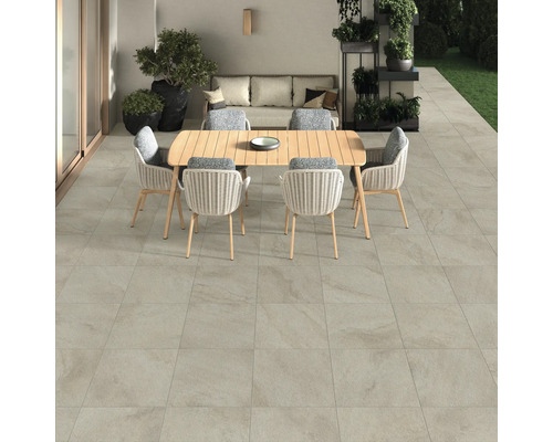 Terrasse mit Bodenfliesen, Gartentisch und Stühlen.
