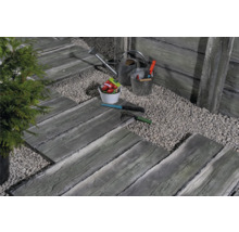 Gartenszene mit Trittplatten in Holzoptik, Kiesweg, Gießkanne und Gartengeräten