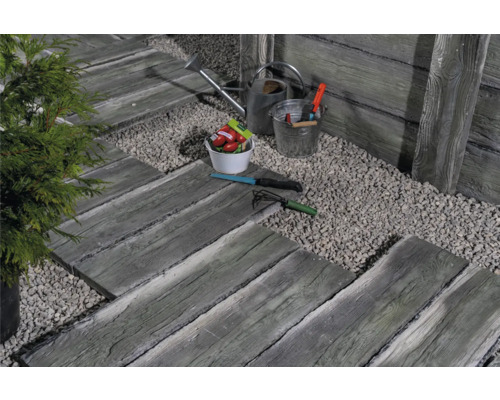 Gartenszene mit Trittplatten in Holzoptik, Kiesweg, Gießkanne und Gartengeräten