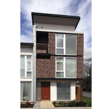 Modernes dreistöckiges Haus mit Ziegelmauerwerk und großen Fenstern.