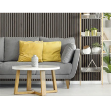 Wohnzimmer mit grauer Couch, gelben Kissen, weißem Tisch und Holzpaneelwand