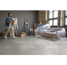 Umzugsszene mit verpacktem Sofa, Stühlen, Leiter und Umzugskartons in einem Raum.