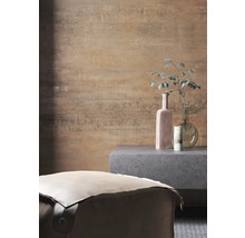 Raumansicht mit einem Pouf, einem Beistelltisch und Dekorationsgegenständen vor einer gemusterten Wand