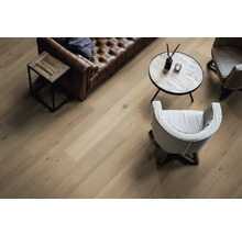 Wohnraum mit Holzboden, Sofa, Sesseln und Tisch