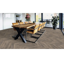 Heller Raum mit Holzboden im Fischgrätmuster, großem Esstisch und Stühlen.