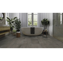 Badezimmer mit freistehender Badewanne, Waschtisch, Pflanzen und grauem Bodenbelag.