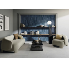 Wohnzimmer mit Sofa, Sessel, Couchtisch, Bücherregal und blauen Wandfliesen