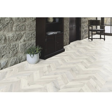 Heller Raum mit Parkettboden im Fischgrätmuster, Steintreppe und dunklem Holzschrank.