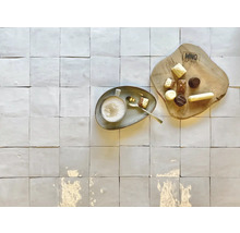 Blick von oben auf helle Bodenfliesen mit Tasse Kaffee und Pralinen