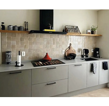 Helle Küche mit grauen Schränken, einer Arbeitsplatte, einem Fliesenspiegel und Regalen zur Aufbewahrung von Küchenutensilien