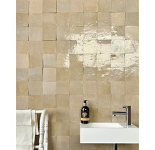 Badezimmerwand mit quadratischen Fliesen, Waschbecken und Armatur