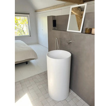 Badezimmer mit freistehendem, zylinderförmigem Waschbecken, Spiegel und Armatur.
