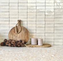 Dekoratives Stillleben mit Holzbrett, Kerzen und Ziegelwand im Hintergrund