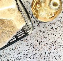 Ansicht von oben auf einen Raum mit Terrazzoboden, einem Sessel mit Überwurf und einem Beistelltisch