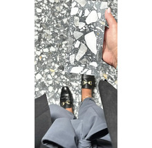 Fliesenmuster mit Terrazzo Optik in der Hand über Bodenfliesen