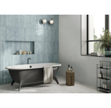 Badezimmer mit blauen Fliesen, freistehender Badewanne und Fenster für eine helle, freundliche Atmosphäre.