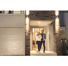 Hausfassade mit Außenbeleuchtung und Paar vor der Haustür