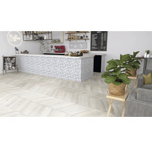 Innenaufnahme eines Cafés mit Holzboden in Fischgrätmuster, einer Theke mit gemusterten Fliesen und Zimmerpflanzen