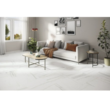 Heller Wohnraum mit weißem Sofa, Couchtisch und weißem Bodenbelag in Marmoroptik.