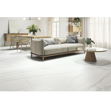 Wohnzimmer mit Sofa, Tisch und Bodenfliesen in Marmoroptik.