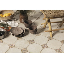 Dekorative Bodenfliesen mit floralen Akzenten, kombiniert mit Geschirr, Schalen und einem Holzhocker, schaffen eine gemütliche Küchenatmosphäre.