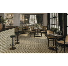 Innenansicht eines Restaurants mit floral gemusterten Fliesen, Tischen, Stühlen und Barhockern.