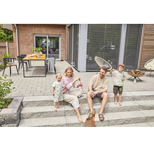 Familie spielt mit Seifenblasen auf einer Terrasse mit Steinplatten und Treppe