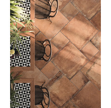 Boden mit Terrakotta Fliesen, Tischen und Stühlen.