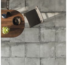 Ansicht von oben auf eine Bodenfläche mit quadratischen Fliesen, einem Tisch mit Dekoration und einem Stuhl.