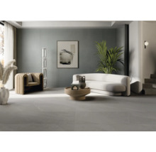 Heller Wohnraum mit Sofa, Sessel, Tisch und grauen Bodenfliesen