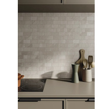 Küchenszene mit Fliesenwand, Kochfeld und Küchenutensilien auf der Arbeitsplatte.