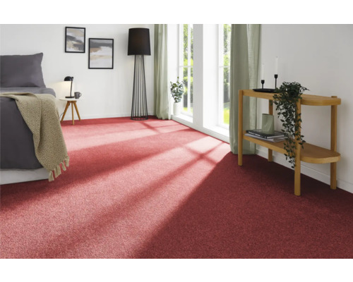 Raumansicht mit rotem Teppichboden, Bett, Beistelltisch und Dekoration