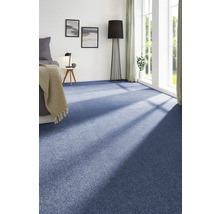 Helles Schlafzimmer mit blauem Teppichboden, Bett, Beistelltisch und Stehlampe.