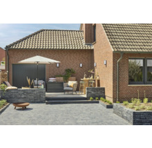 Gestalteter Gartenbereich mit Pflastersteinen, Gartenmöbeln und Beleuchtung