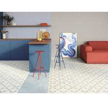 Helle Küche und Wohnzimmer mit floral gemusterten Bodenfliesen, Tresen mit Barhockern und Sofa.